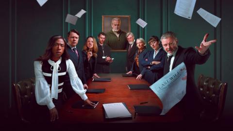 A group of people standing around a wooden table in a dark green room, throwing sheets of paper into the air