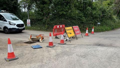 Roadworks with several traffic cones and road closed signs.