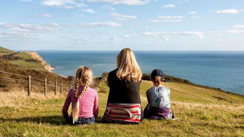 A mother and her two daughters view the Jurassic Coast, Dorset.