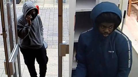 Two youths caught on CCTV committing a robbery in a mobile phone shop. One is wearing a blue hooded coat and the other a grey hoody and black trousers, both with their hoods pulled up.