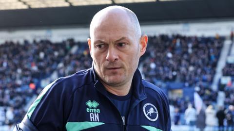 Millwall boss Alex Neil looking straight at the camera wearing a dark blue Millwall training top