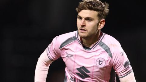 Laurence Maguire in action for MK Dons in their pink away strip