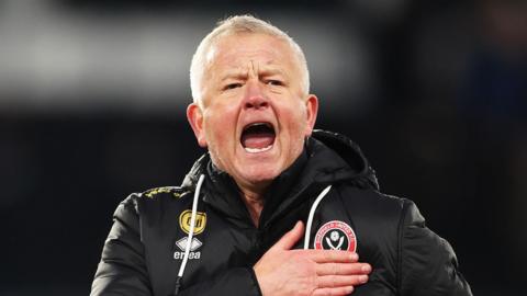 Sheffield United boss Chris Wilder patting the club crest on his jacket after winning Portsmouth