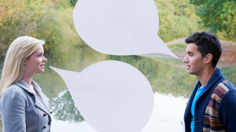 A woman on the left and a man on the right are talking to each other in front of a pond in a park. They both have empty speech bubbles coming from their mouths. The woman is blonde and wearing a blue jacket. The man is wearing a cardigan and blue t-shirt and has dark, short hair. 