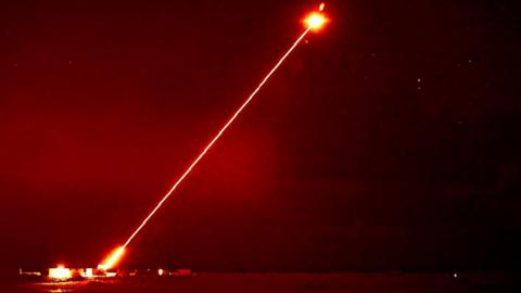 A night shot showing the DragonFire laser firing at an aerial target