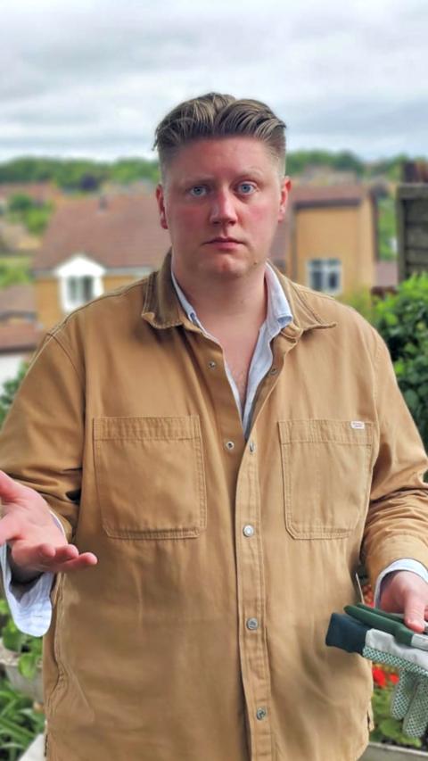Man with blonde hair and camel jacket over shirt looking to camera outdoors
