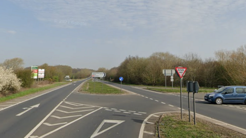 A general view of the A12 near Saxmundham. Part of the road continues straight on while there is a lane for drivers wanting to turn right into another road. A car can be seen coming out of the junction from the right-hand side.
