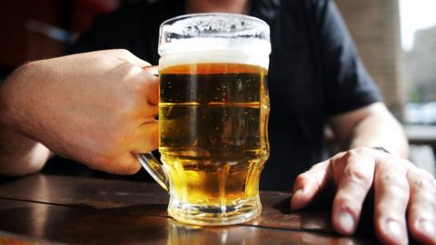 A man holding a glass of beer in a Moscow outdoor pub