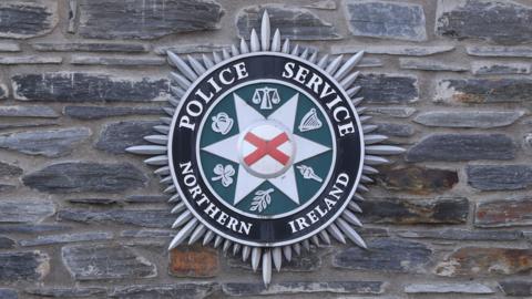 A PSNI logo on a brick wall