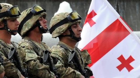 Georgian troops parade in front of their national flag