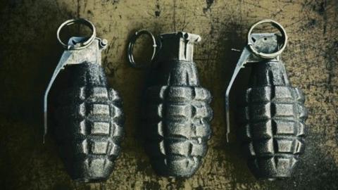 Three hand grenades, side by side, against a hard surface 