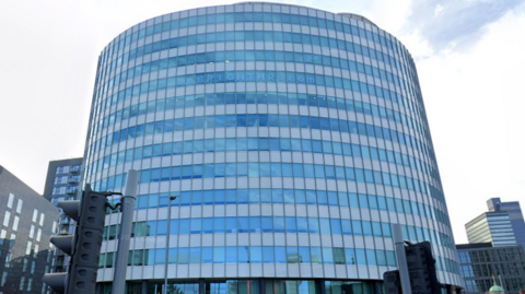 The headquarters of Bright HR in Manchester. It is a rounded, 13-storey steel and glass building. 