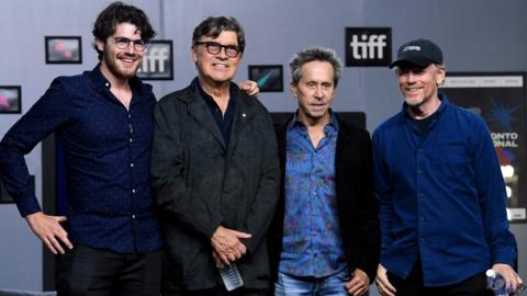 Daniel Roher, Robbie Robertson, and exec producers Brian Grazer and Ron Howard