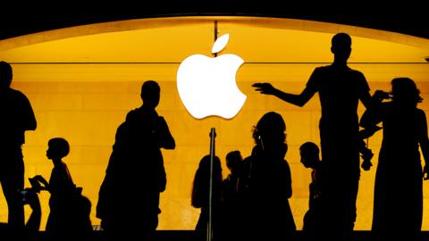 Silhouetted figures by the Apple logo
