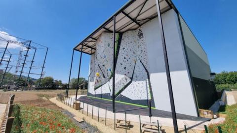An image of a white outdoor climbing wall in a field.