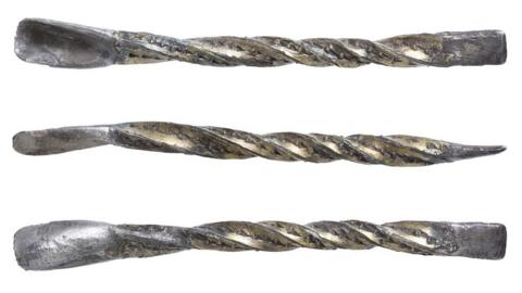 A medieval silver gilt ear scoop. It is a twisted piece of silver gilt with a small scoop at one end and a flat end a bit like a flat head screw driver at the other.  Tiny dots have been punched into the silver twists 