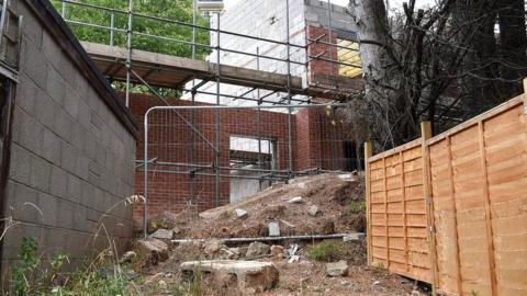 A mound of earth piled up against trees in the back garden of a house on Mascot Road