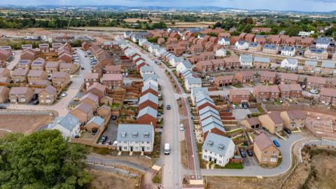 An aerial view of a new-build housing development. The development is still under construction and heavy machinery is visible on the edge of the image. 