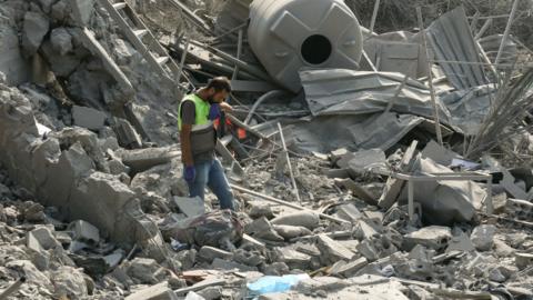 An emergency worker looks through rubble in the aftermath of an airstrike on Ansar in Lebanon
