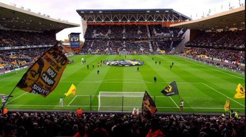 The Molineux stadium filled with fans waving flags and players on the pitch