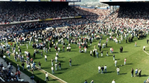 Image shows football fans, ambulances, paramedics and police officers on the pitch after the 1989 FA Cup semi-final at Hillsborough stadium was abandoned.
