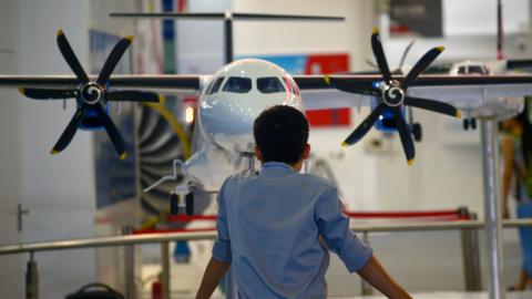 A man looks at an aircraft scale model at the Aviation Industry Corporation of China booth during an expo in Beijing in 2015