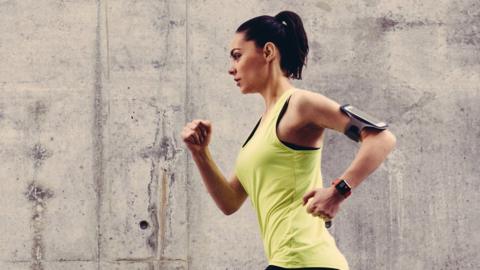 A women wearing a mobile phone and smart watch as she jogs