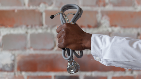 A medic's hand holding a stethoscope