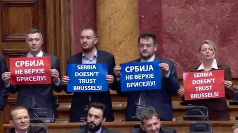 Four Serbian MPs hold signs protesting against the EU