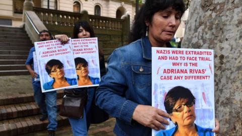 Members of the Chilean Australian community from the National Campaign for Truth and Justice in Chile carry pictures of Adriana Rivas at Central Local Court in Sydney, Tuesday, April 2, 2019. (AAP Image/Dean Lewins)