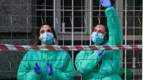 Medical staff from La Princesa hospital react as neighbours applaud from their balconies in support for healthcare workers on 5 April