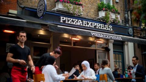 Customers sit outside Pizza Express restaurant in Central London