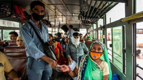 A bus conductor issues tickets to a female passenger in Uttar Pradesh.