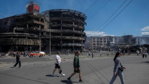 Residents cross a street at the site of a Russian missile and drone strike