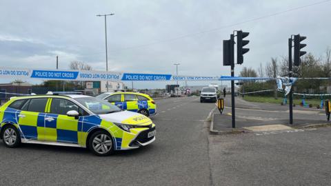 Two police cars and a police cordon on the intersection of a main road in Filton, north Bristol.