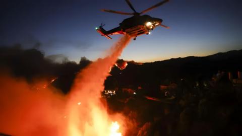 Helicopter flies over blaze.