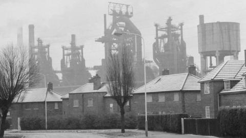 The steelworks in Corby against the skyline, with a housing estate in the foreground