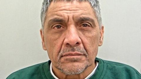 A mugshot of Sabbir Patel has short greying hair and a beard and is wearing a dark green jumper. 