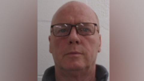 A mugshot of Bernard McDonagh. He is looking straight at the camera, is wearing glasses and has a nearly bald head.