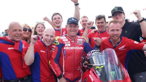 John McGuinness celebrates his 2024 NW200 Superstock team with team members and family