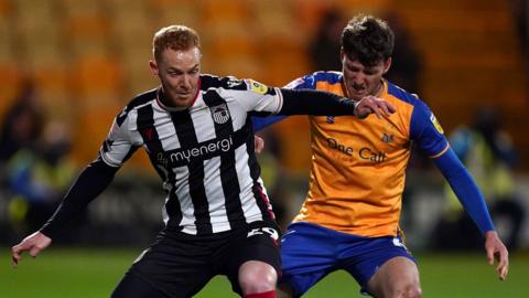Mansfield Town’s Riley Harbottle and Grimsby Town’s Ryan Taylor (left) challenge for the ball