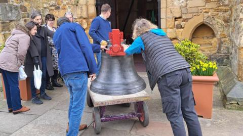 Volunteers push a large bell on a trolley through the main entrance to St. Peter and St. Paul's church in Tonbridge