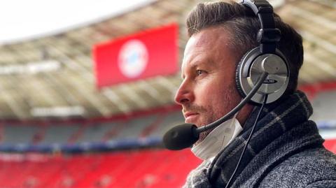 A side profile picture of a man wearing large over the ear headphones with a microphone attached to the side.