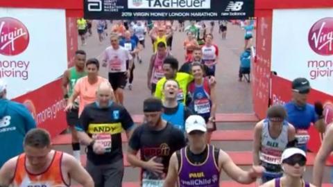 Steven Quayle (in blue vest, centre) crosses the London Marathon finish line