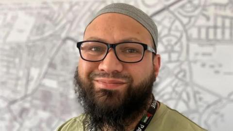Councillor Mothin Ali wears glasses and a head covering.