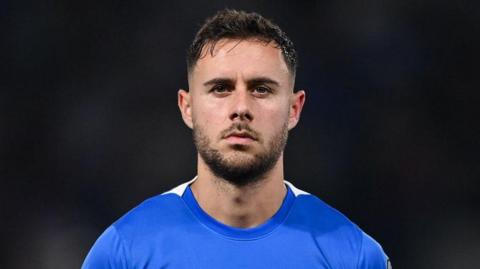 George Baldock playing in Greece while wearing a blue top 