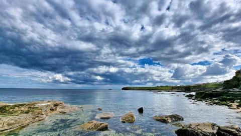 A cloudy sky over a calm sea.