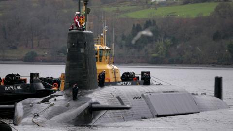 A Vanguard class submarine in dock at Faslane. Three submariners in uniform can be seen on the deck
