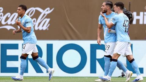 Rayan Cherki and Phil Foden celebrate together, with Rico Lewis to the left