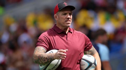 Paul James holds balls under his arms in Wales' warm-up